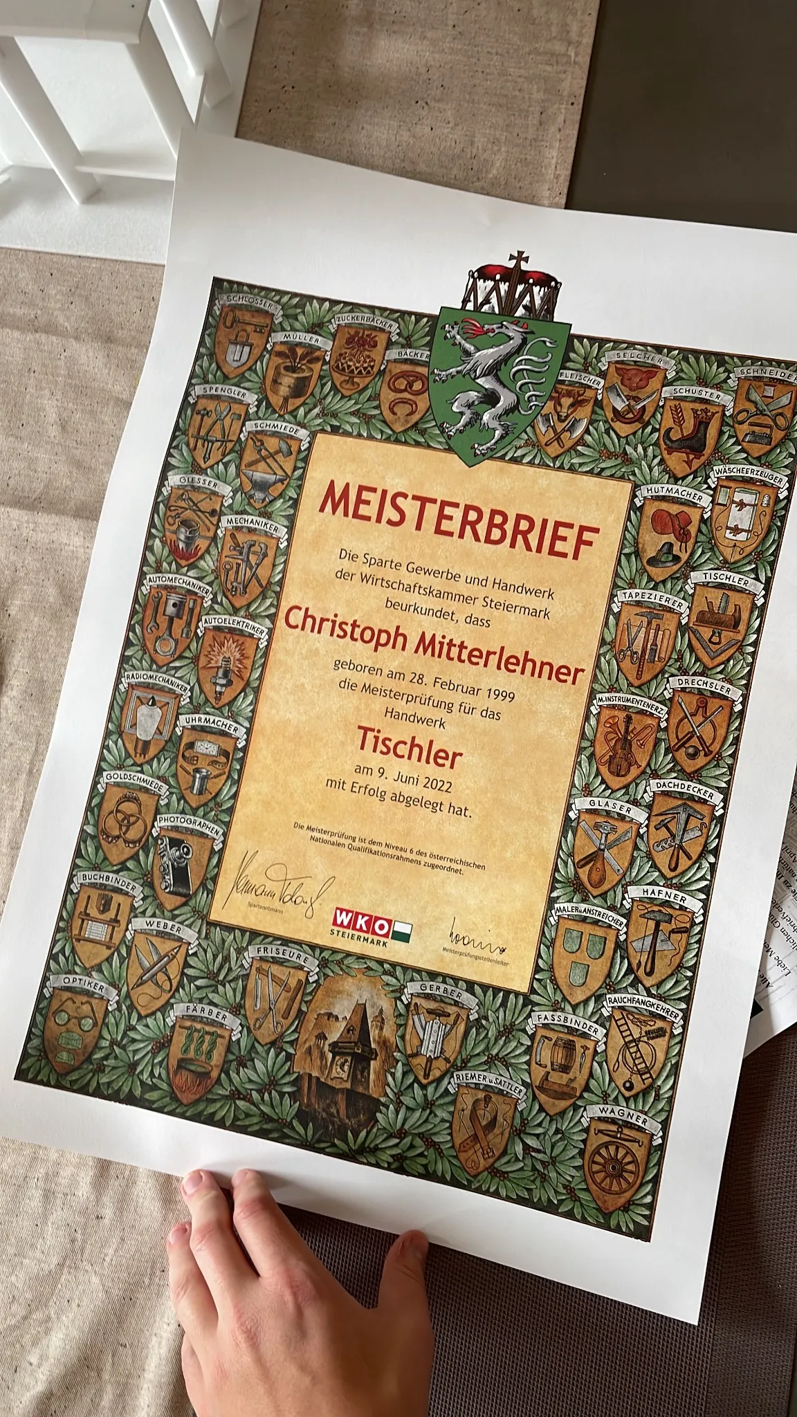 Fotografierter Meisterbrief des Tischlerhandwerks auf einer Arbeitsfläche